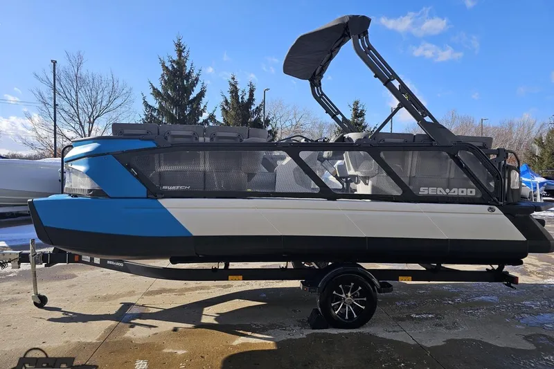 Slide: The Image of 2023 Sea-Doo Switch Cruise 21 pontoon boat on trailer, blue and white design. - 26