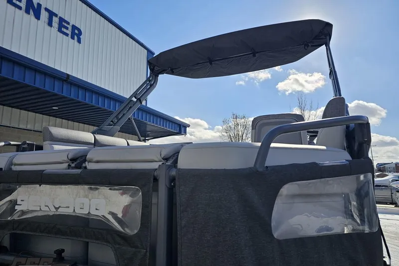 Slide: The Image of 2023 Sea-Doo Switch Cruise 21 pontoon boat with canopy, parked near a building under a blue sky. - 41