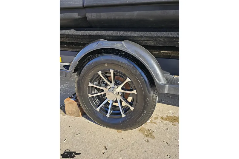 Slide: The Image of 2023 Sea-Doo Switch Cruise 21 trailer wheel on pavement, supported by a wooden block. - 6