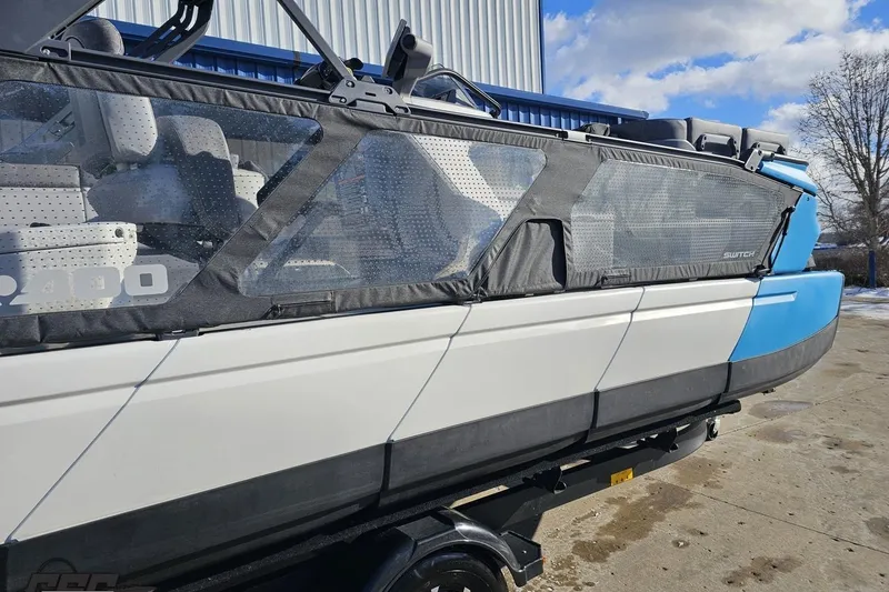 Slide: The Image of 2023 Sea-Doo Switch Cruise 21 pontoon boat with blue and white exterior, docked outdoors. - 8