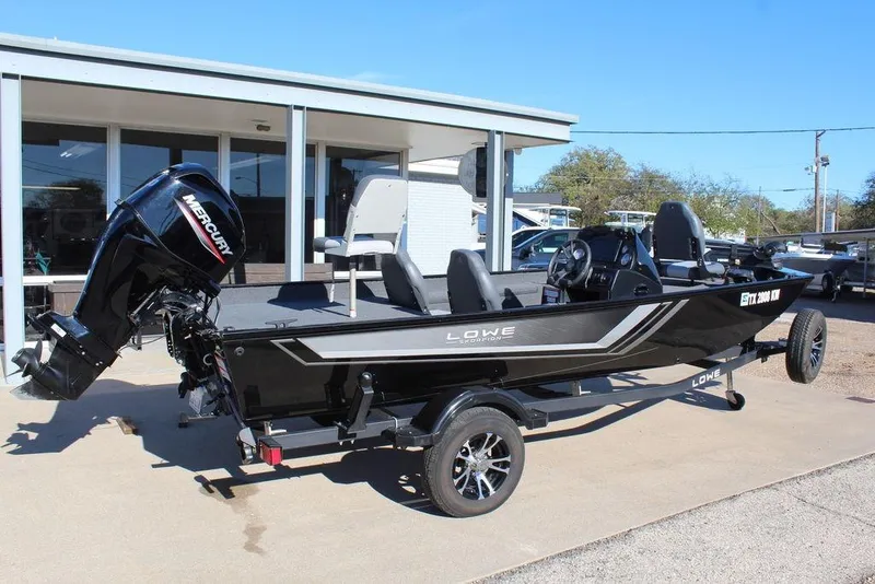 Slide: The Image of 2023 Lowe Skorpion 17 boat with Mercury engine, parked on a trailer outside a building. - 7