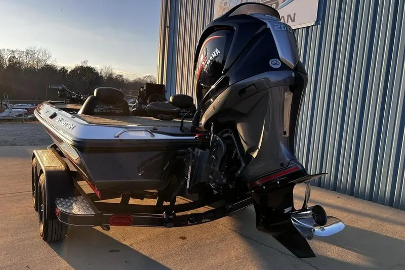 Slide: The Image of 2023 Skeeter ZX200 boat with powerful outboard motor, parked near a blue building. - 19