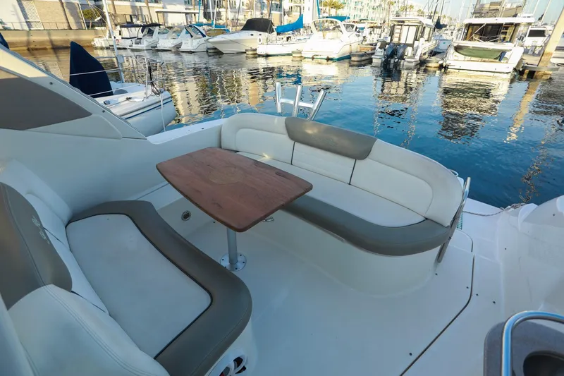 Slide: The Image of 2007 Sea Ray Sundancer 310 boat interior with seating and wooden table, docked at marina. - 11