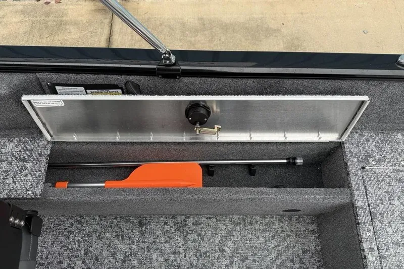 Slide: The Image of Storage compartment in 2026 Tracker Pro Guide V-16 SC boat, featuring an orange safety paddle. - 16