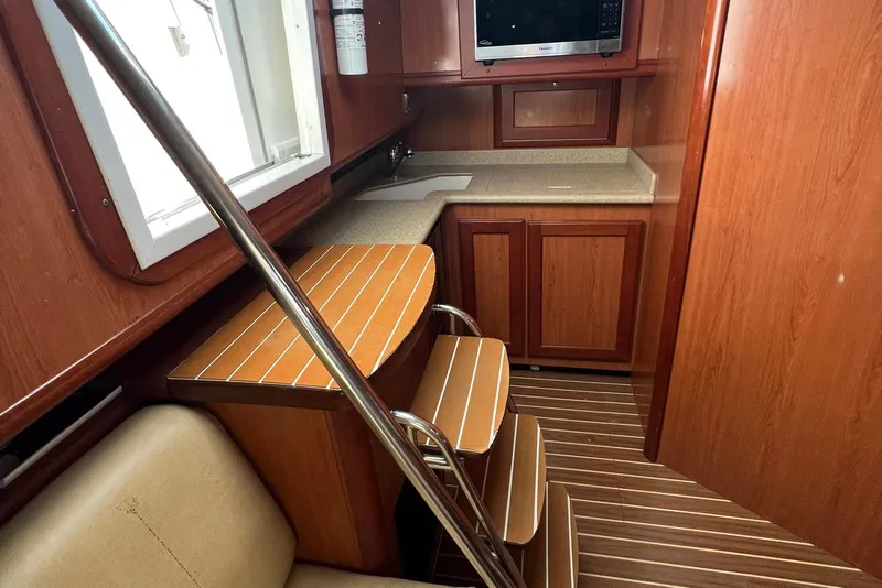 Slide: The Image of 2007 Luhrs 41 Hardtop interior with wooden cabinetry, compact kitchen, and seating area. - 6
