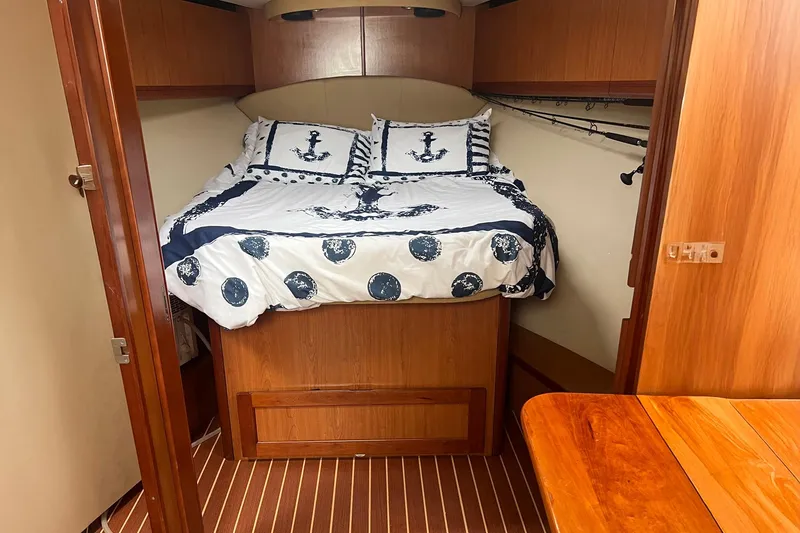 Slide: The Image of 2007 Luhrs 41 Hardtop cabin with nautical-themed bedding and wooden interior. - 7