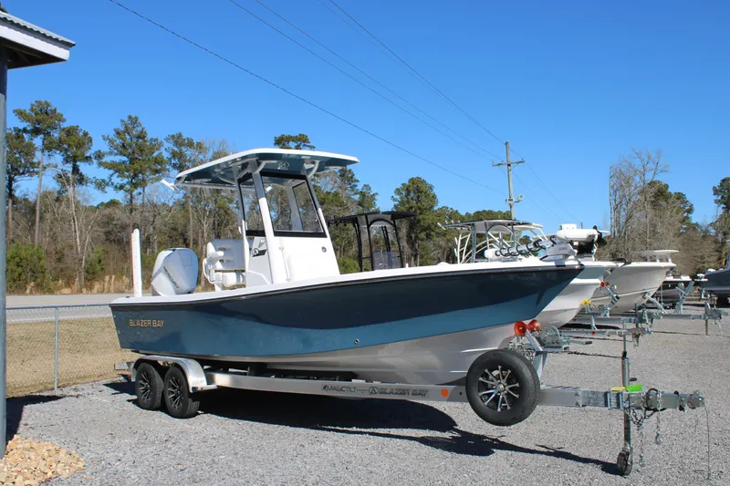 Slide: The Image of 2026 Blazer Bay 2440 boat on trailer, parked outdoors under clear blue sky. - 2