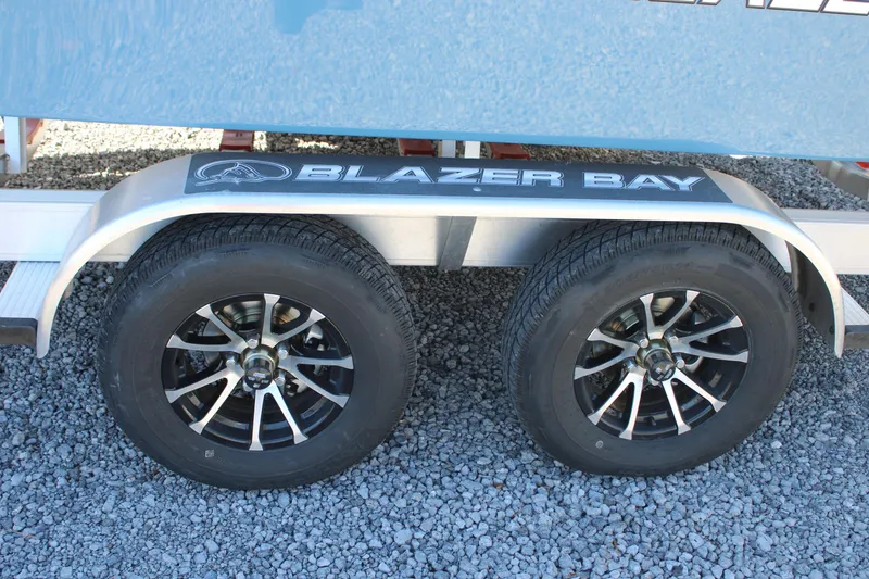 Slide: The Image of 2026 Blazer Bay 2440 trailer wheels on gravel surface. - 54
