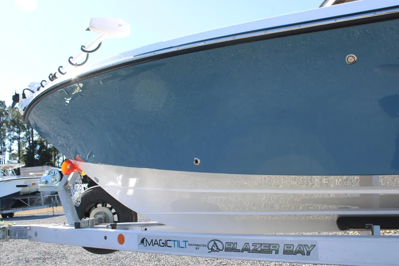 Slide: The Image of 2026 Blazer Bay 2440 boat on trailer, side view with blue and white hull. - 55