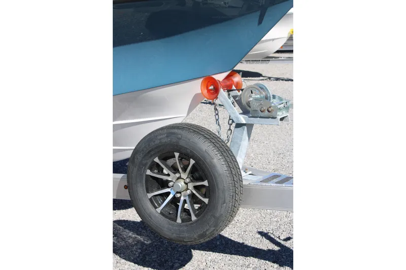 Slide: The Image of 2026 Blazer Bay 2440 boat trailer with wheel and winch on gravel surface. - 56