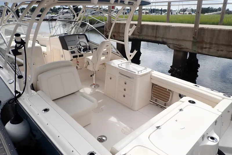 Slide: The Image of 2021 Grady-White Freedom 275 boat interior with seating and helm, docked by the water. - 2