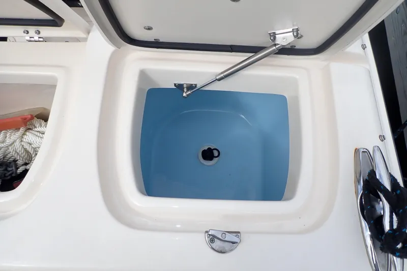 Slide: The Image of 2021 Grady-White Freedom 275 boat storage compartment with open lid and visible ropes. - 40