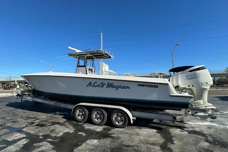 Slide: The Image of 2005 Contender 36 Cuddy boat on trailer with Suzuki engines, clear blue sky background. - 3