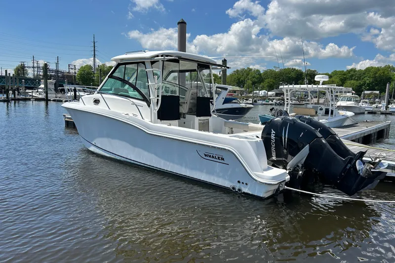 Slide: The Image of 2015 Boston Whaler 285 Conquest boat docked in a marina under a blue sky. - 1