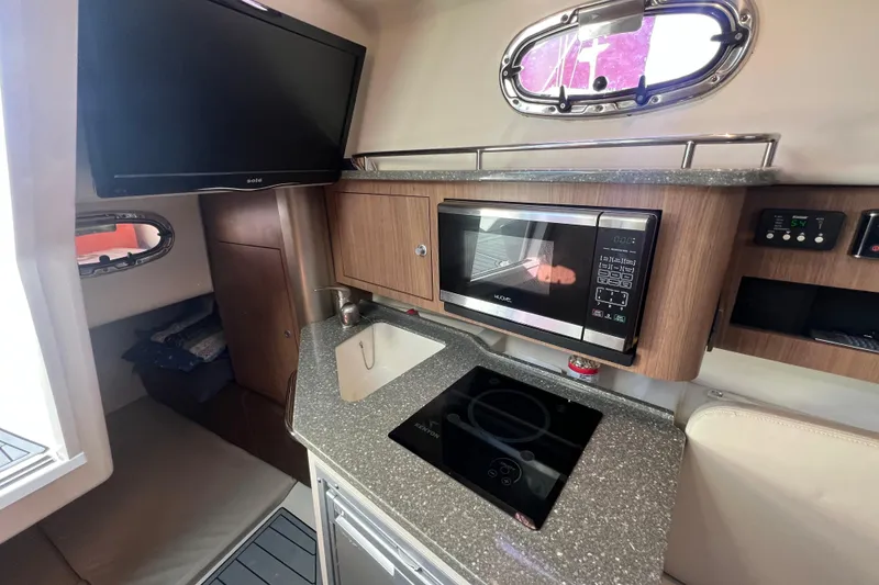 Slide: The Image of 2015 Boston Whaler 285 Conquest interior with kitchenette, microwave, and TV. - 13