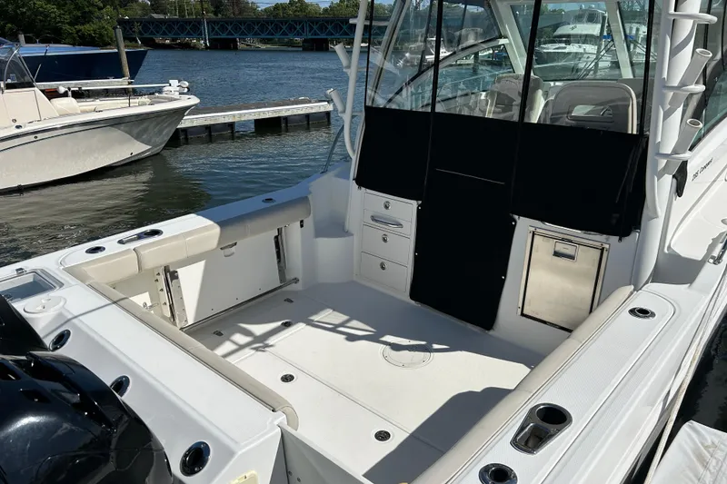 Slide: The Image of 2015 Boston Whaler 285 Conquest boat interior at dock, featuring seating and storage. - 4