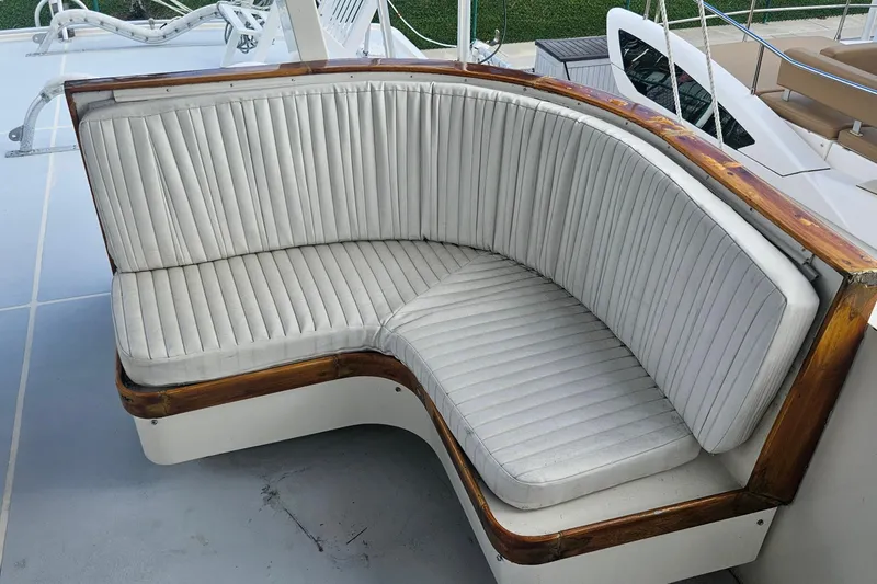 Slide: The Image of Curved seating on 1988 Cheoy Lee 51 Long Range Cockpit Motor Yacht, featuring white upholstery and wooden trim. - 26