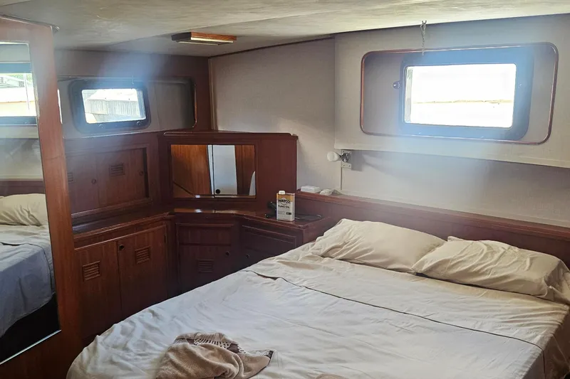 Slide: The Image of Interior cabin of 1988 Cheoy Lee 51 Long Range Cockpit Motor Yacht, featuring a cozy bed and wooden furnishings. - 30