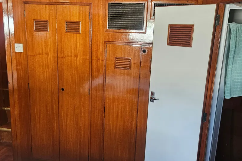 Slide: The Image of Interior of 1988 Cheoy Lee 51 Yacht, featuring wooden paneling and a white door. - 33