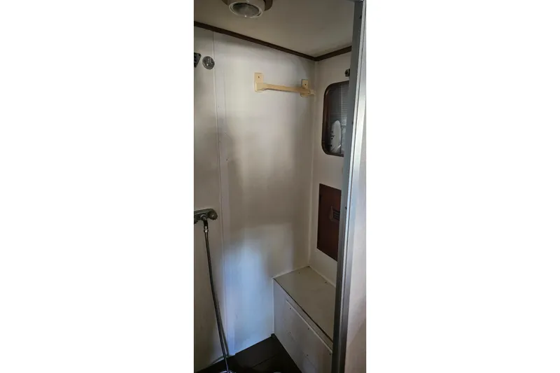 Slide: The Image of 1988 Cheoy Lee 51 Yacht shower area with white walls and storage compartment. - 34