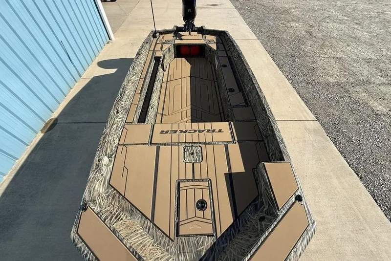 Slide: The Image of 2026 Tracker Grizzly 1756 T Marsh boat, camo design, parked on concrete near blue building. - 20