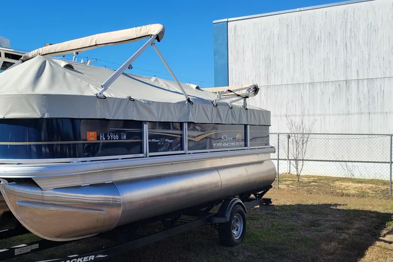 Slide: The Image of 2024 Sun Tracker Bass Buggy 18 DLX pontoon boat with cover, parked outdoors. - 3