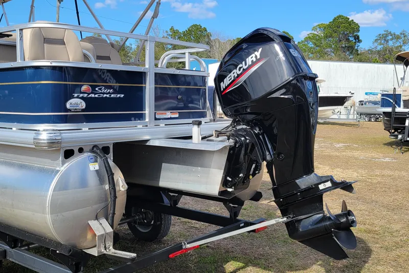 Slide: The Image of 2024 Sun Tracker Bass Buggy 18 DLX with Mercury outboard motor, parked outdoors. - 5