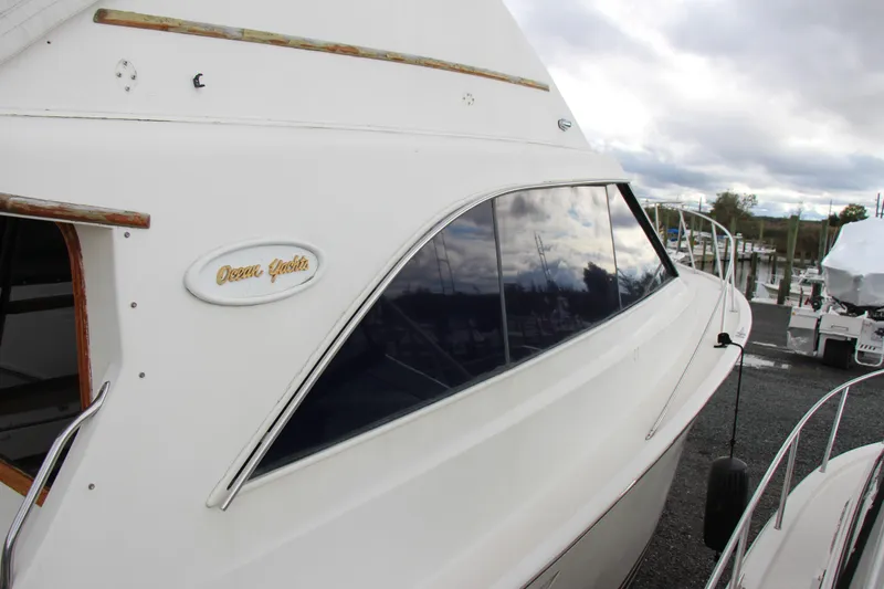 Slide: The Image of 1989 Ocean Yachts 35 Super Sport boat docked, showcasing sleek design and reflective windows. - 5