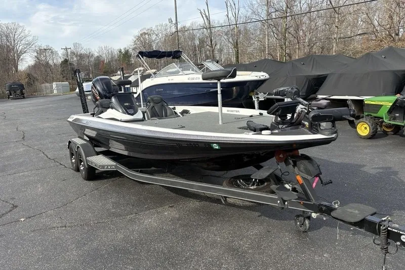 Slide: The Image of 2023 Skeeter ZXR21 boat on trailer in parking lot, surrounded by other boats and equipment. - 5