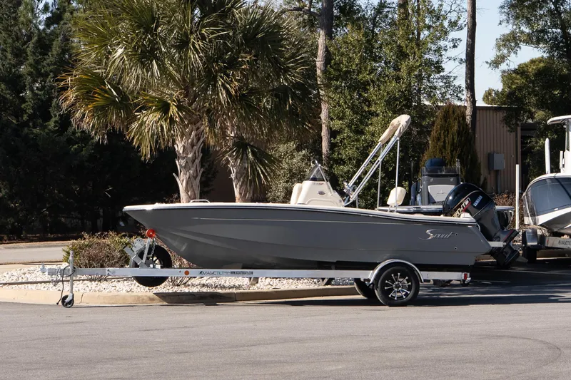 The Image of 2026 Scout 188 Sportfish boat on trailer, parked near palm trees. - 1