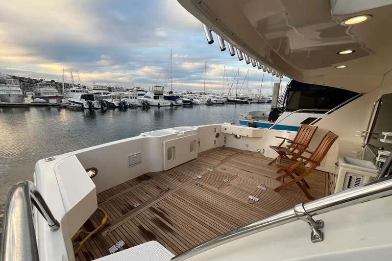 Slide: The Image of 2001 Mikelson Luxury Sportfisher yacht deck with wooden chairs, docked at marina. - 4