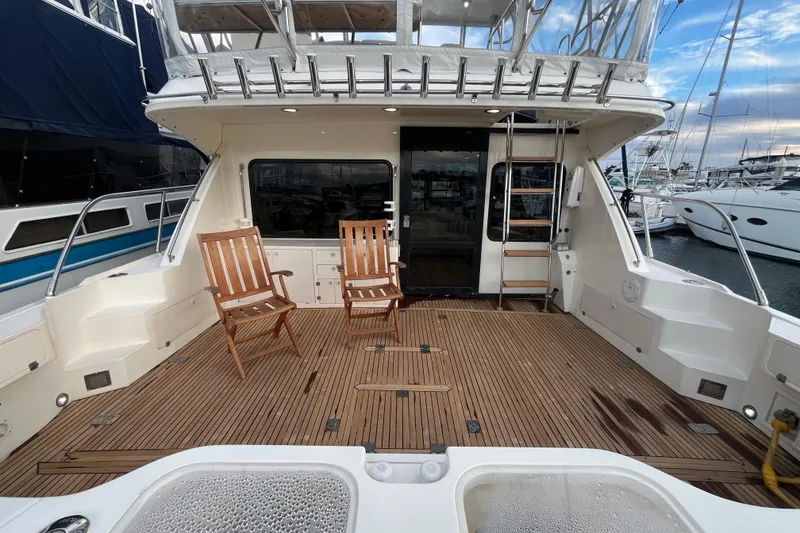 Slide: The Image of 2001 Mikelson Luxury Sportfisher yacht deck with wooden chairs and marina view. - 7