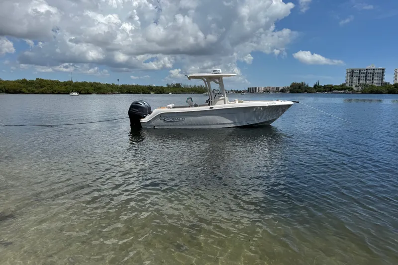 Slide: The Image of 2021 Robalo R242 Center Console boat anchored on calm water under a cloudy sky. - 2