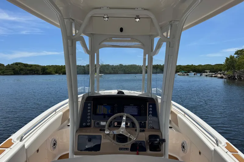 Slide: The Image of 2021 Robalo R242 Center Console boat on calm water, featuring modern dashboard and steering. - 5