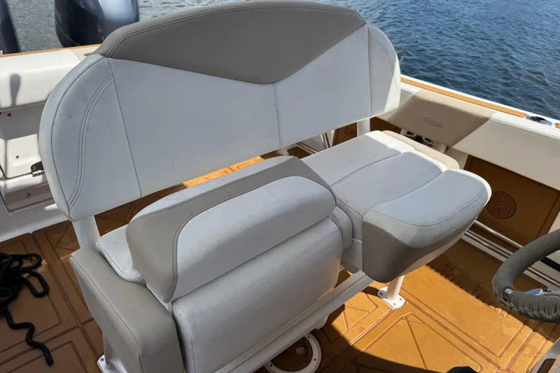 Slide: The Image of 2021 Robalo R242 Center Console boat seat with beige and white upholstery, on water. - 7