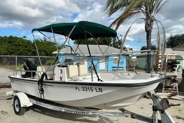The Image of 1999 Boston Whaler 170 Montauk boat on trailer with green canopy, parked outdoors. - 0