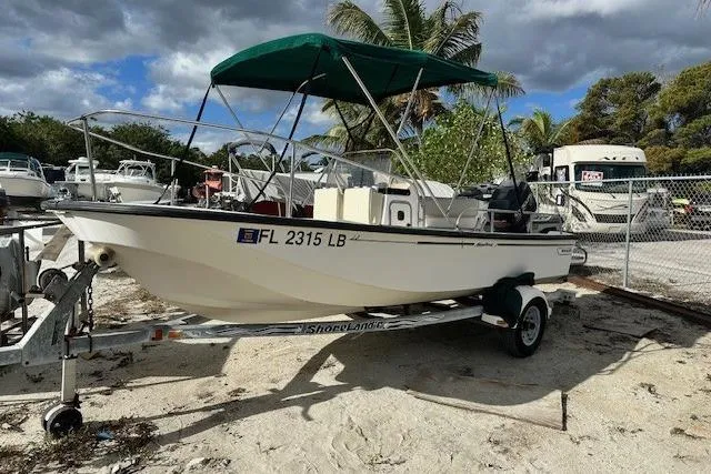 Slide: The Image of 1999 Boston Whaler 170 Montauk boat on trailer with green canopy, parked outdoors. - 3