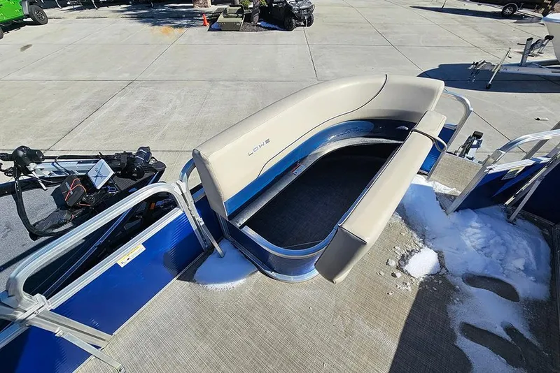 Slide: The Image of 2023 Lowe Ultra 180 Cruise pontoon boat with beige seating and blue accents on a concrete surface. - 15
