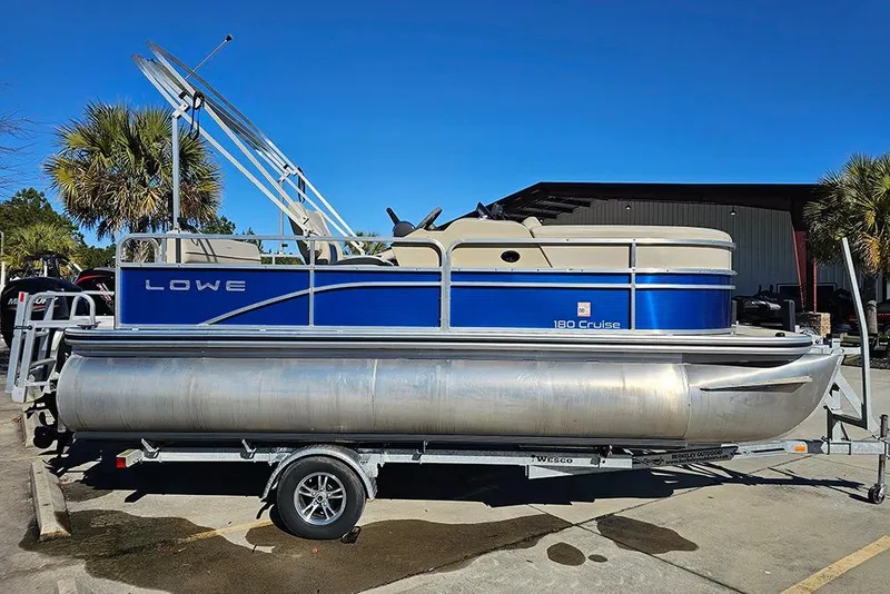 The Image of 2023 Lowe Ultra 180 Cruise pontoon boat on trailer, parked outdoors. - 2