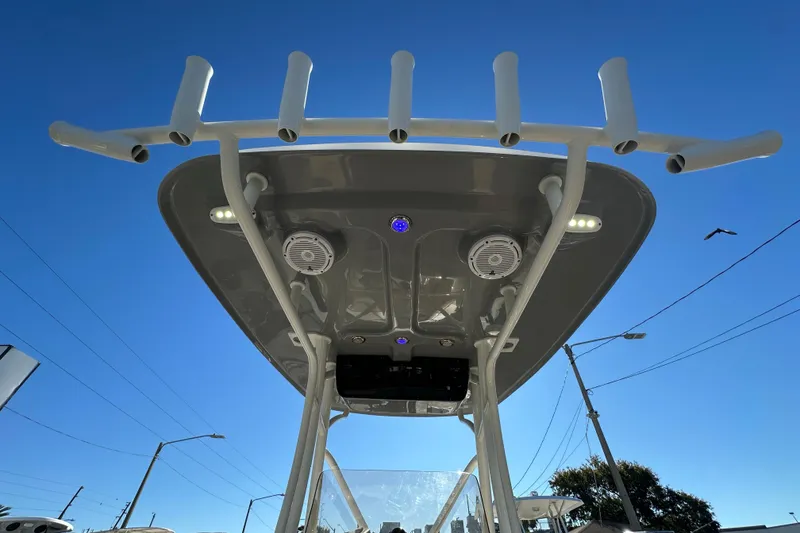 Slide: The Image of T-top of 2020 Pioneer 222 Sportfish boat with rod holders and speakers against blue sky. - 23