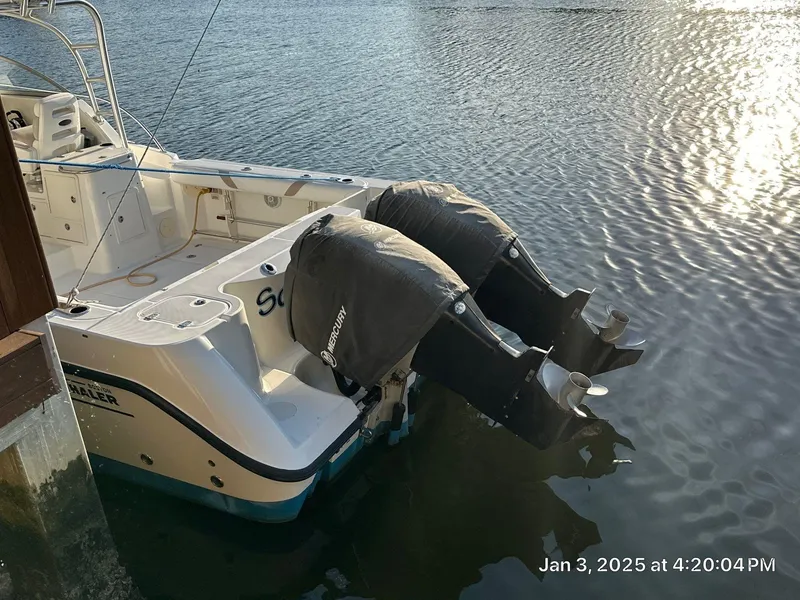 Slide: The Image of 2007 Boston Whaler 305 Conquest with twin outboard motors docked on calm water. - 16