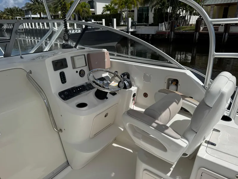 Slide: The Image of 2006 Boston Whaler 305 Conquest helm with steering wheel and controls, docked by water. - 18