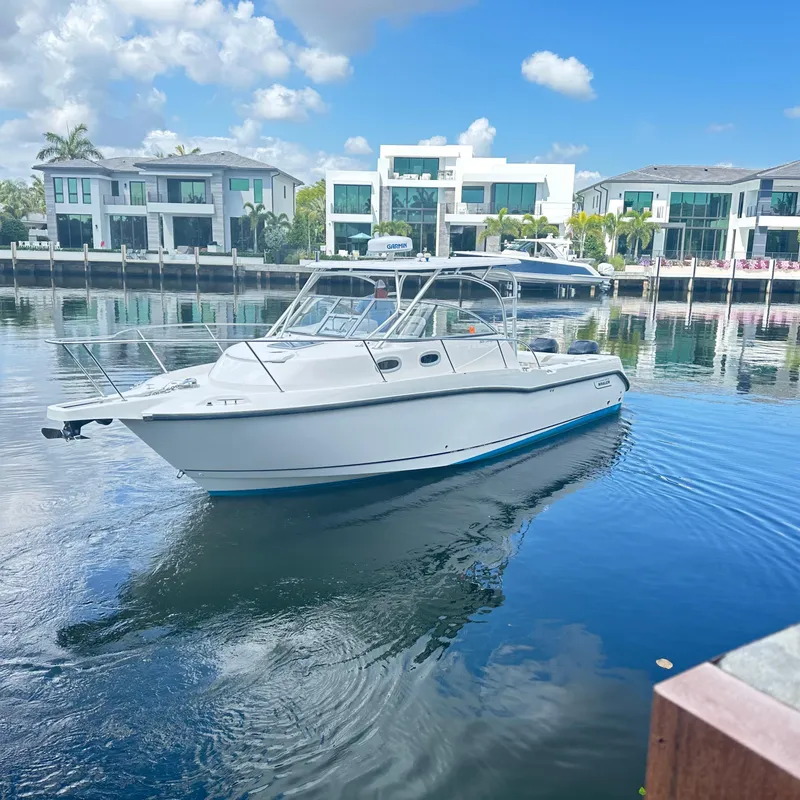 Slide: The Image of 2006 Boston Whaler 305 Conquest boat on calm water near modern waterfront homes. - 2