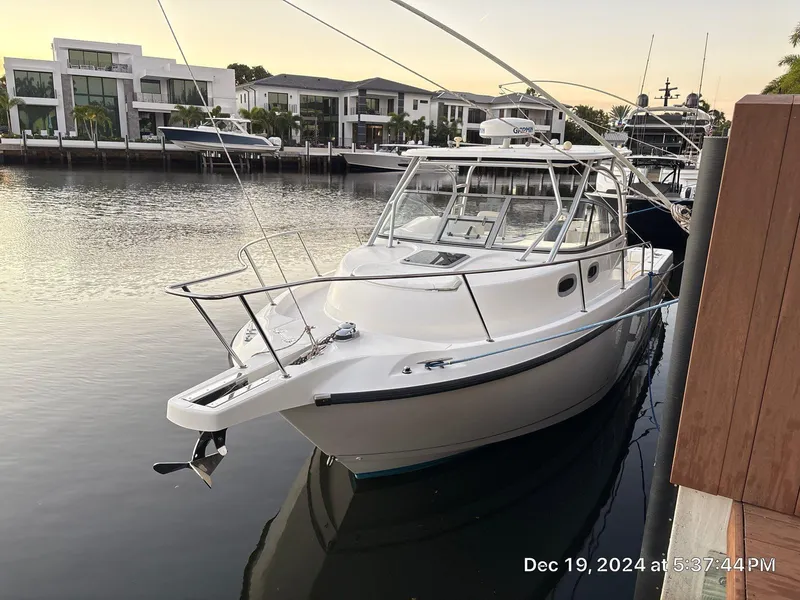 Slide: The Image of 2007 Boston Whaler 305 Conquest docked by waterfront homes at sunset. - 5