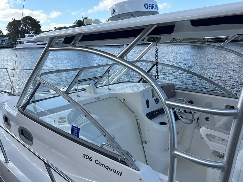 Slide: The Image of 2007 Boston Whaler 305 Conquest boat docked by the water, showcasing sleek design and controls. - 7