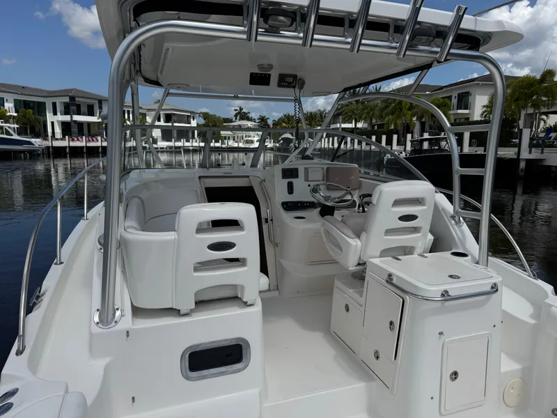 Slide: The Image of 2006 Boston Whaler 305 Conquest boat interior with helm, seating, and storage, docked in marina. - 8