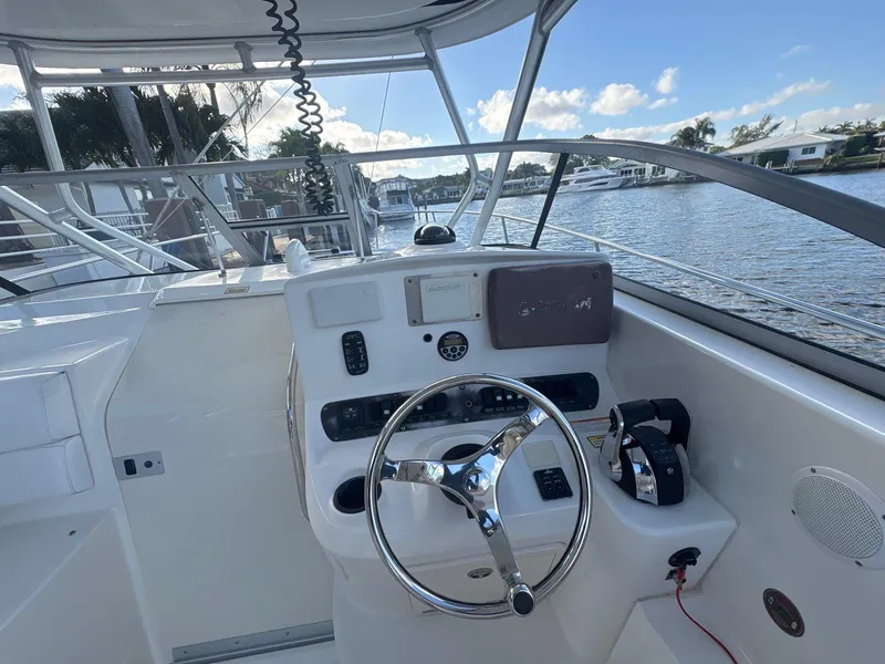 Slide: The Image of 2007 Boston Whaler 305 Conquest helm with steering wheel and controls, docked by the water. - 9