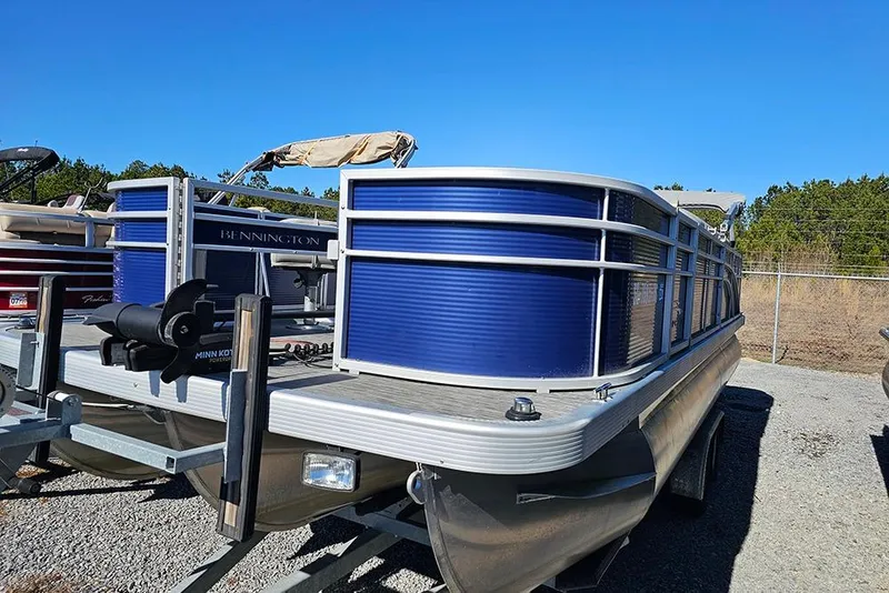 Slide: The Image of 2022 Bennington 22SF pontoon boat with blue panels on a trailer, under clear sky. - 4