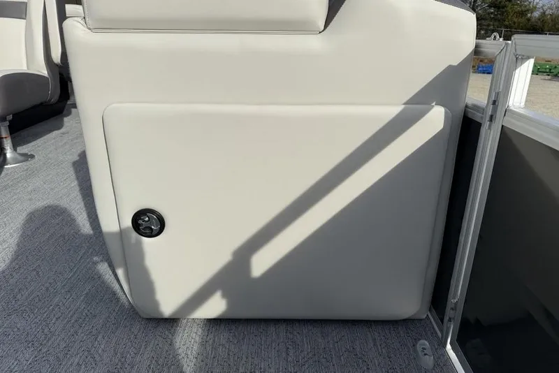 Slide: The Image of 2026 Sun Tracker Fishin' Barge 22 DLX interior storage compartment with gray carpet flooring. - 16