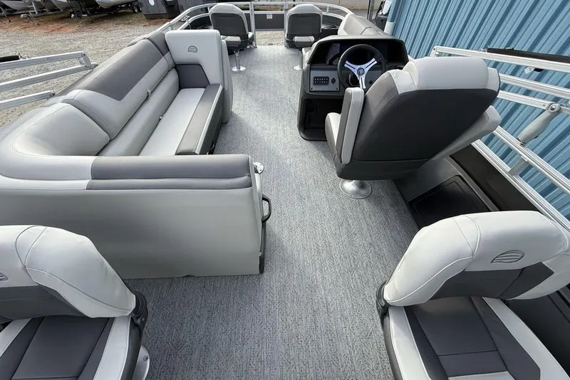 Slide: The Image of 2026 Sun Tracker Fishin' Barge 22 DLX interior with gray seating and steering console. - 28